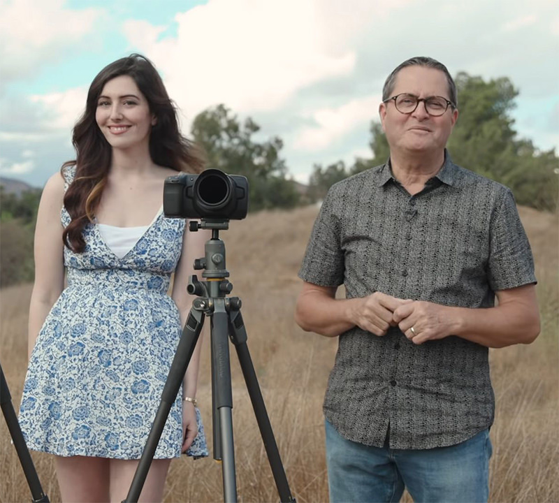 Father and daughter standing next to camera